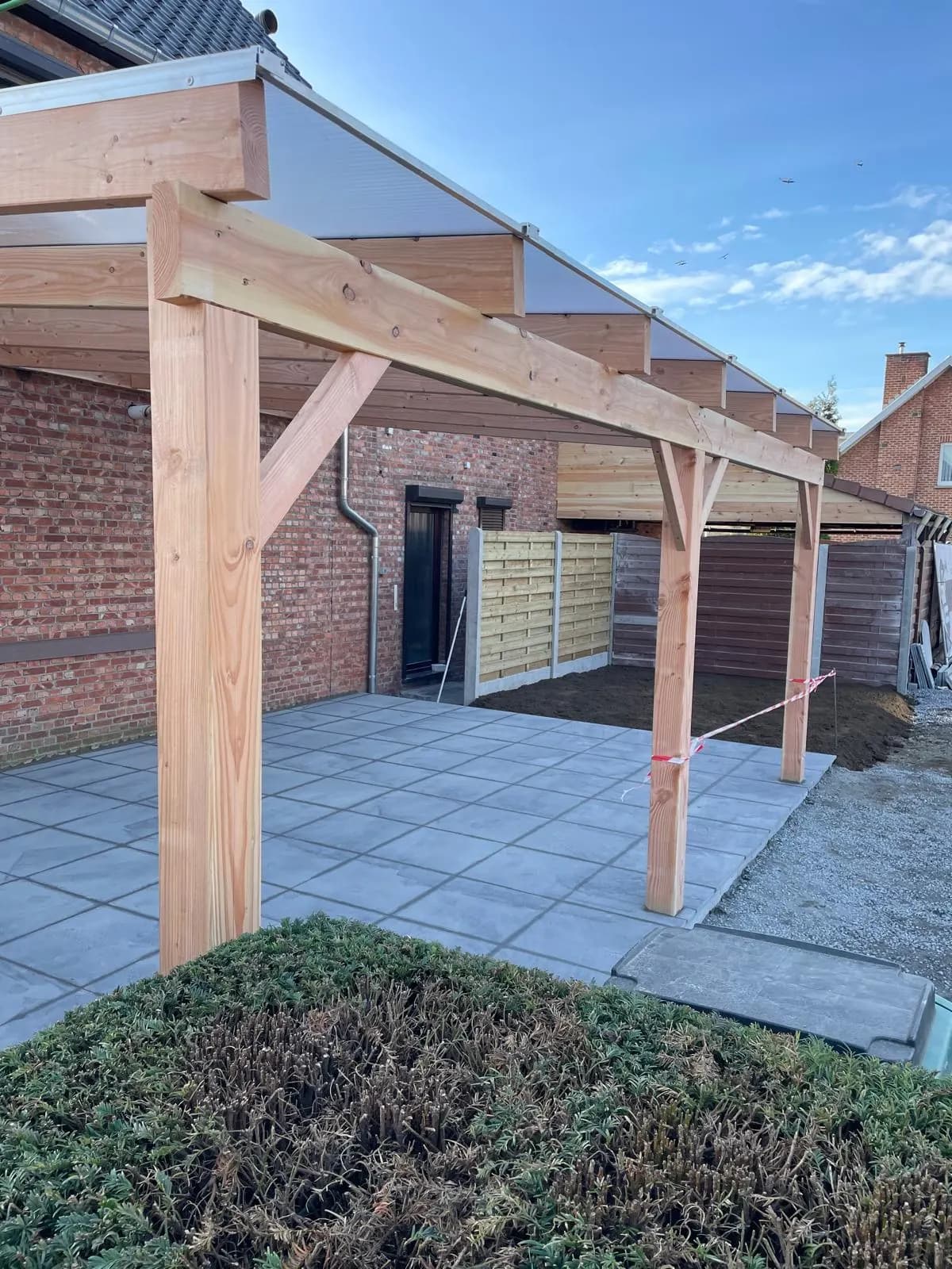 Afdak in douglashout boven een verharde zone naast de woning