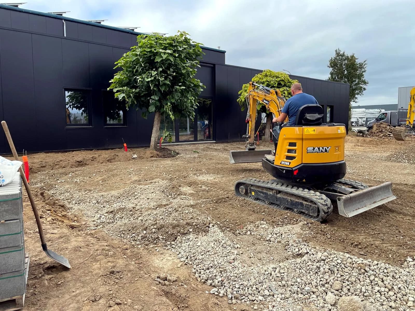 Grondwerk met graafmachine bij een bedrijfsgebouw